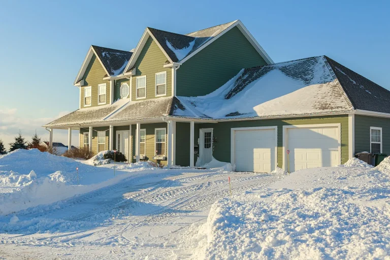 Two-story yellow house with green roof covered in snow during winter